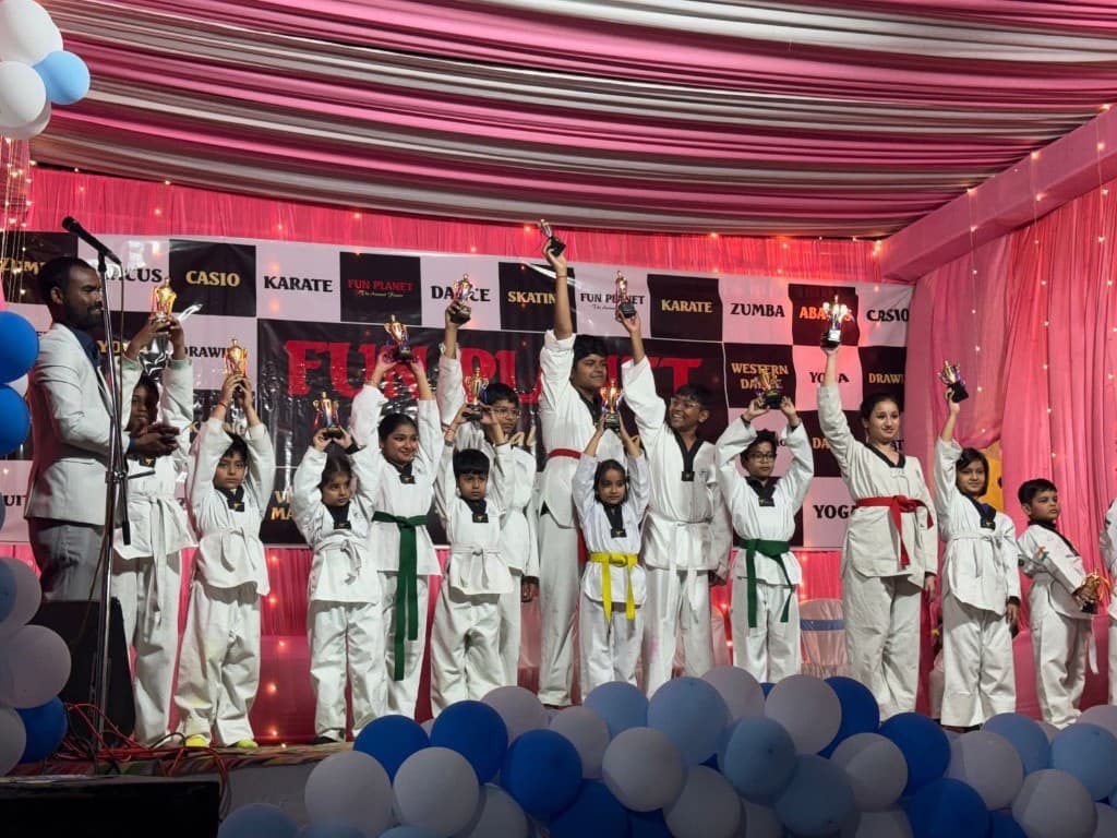Taekwondo students celebrating with trophies on stage at Funplanet annual day