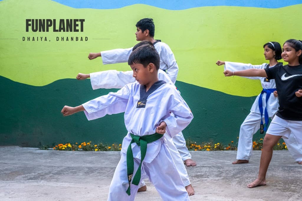 Young Taekwondo student with green belt practicing a punch outdoors at Funplanet